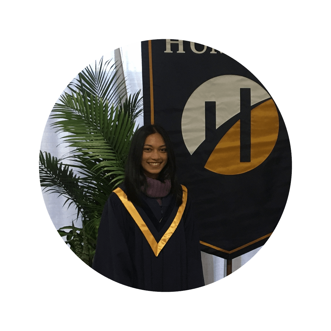 Neeha Dsouza, a woman with brown skin and long black hair, smiles at the camera wearing graduation garb.