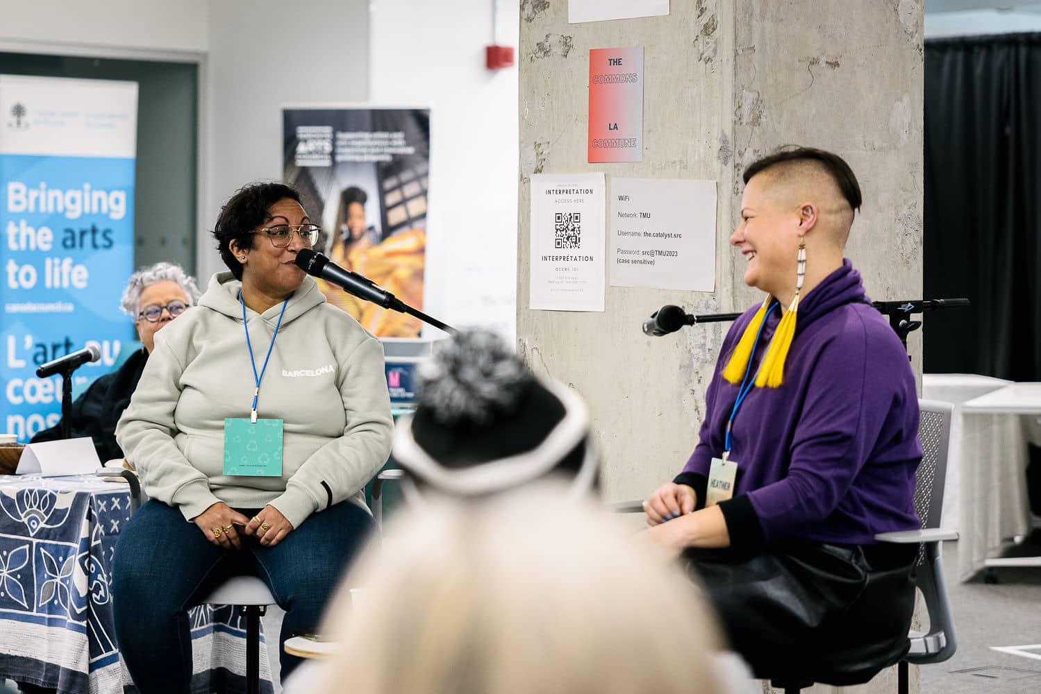 Parul Pandya is speaking into a microphone onstage, mid-conversation with Heather George, at Toronto Metropolitan Conversation during Mass Culture's Convergence in Winter 2023.